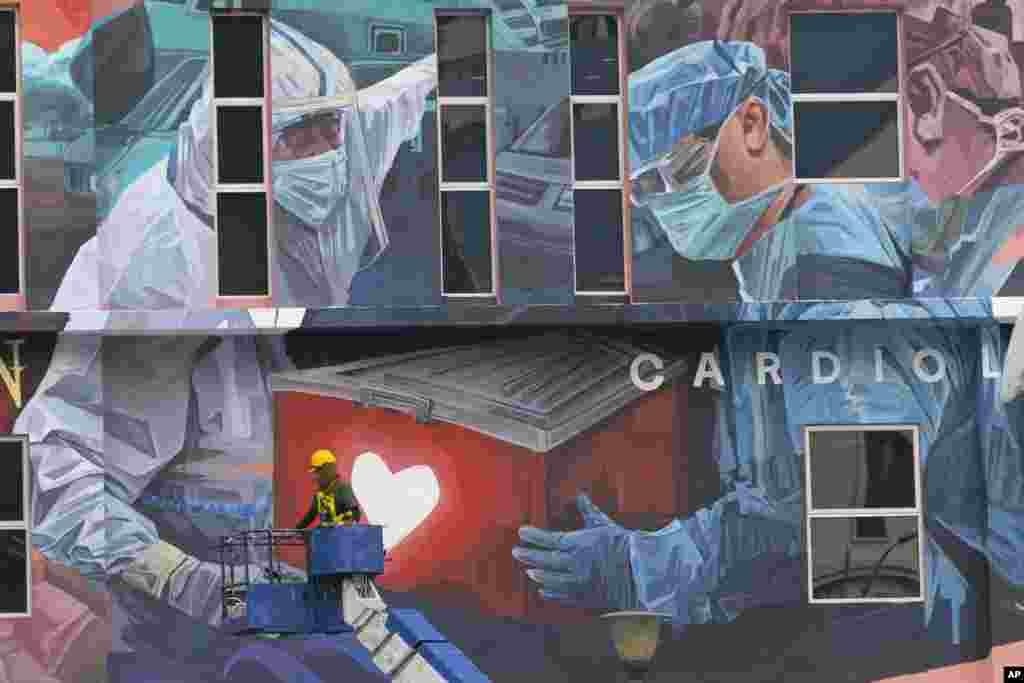 A worker adds finishing touches to giant mural tribute to frontline workers in the COVID-19 pandemic outside a hospital in Kuala Lumpur, Malaysia.