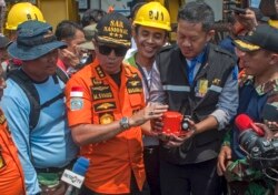FILE - Chief of National Search and Rescue Agency Muhammad Syaugi, center, holds the flight data recorder from the crashed Lion Air jet during a press conference, onboard rescue ship anchored in the waters of Tanjung Karawang, Indonesia, Nov. 1, 2018