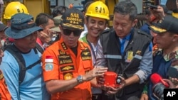 El jefe de la agencia nacional de búsqueda y rescate de Indonesia, Muhammad Syaugi, (centro) sostiene la caja que contiene la grabadora de datos del siniestrado avión de Lion Air durante una conferencia de prensa en Yakarta, Indonesia, el jueves, 1 de noviembre de 2018.