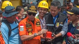 FILE - Chief of National Search and Rescue Agency Muhammad Syaugi, center, holds the flight data recorder from the crashed Lion Air jet during a press conference, onboard rescue ship anchored in the waters of Tanjung Karawang, Indonesia, Nov. 1, 2018