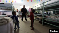 FILE - Father Rito Julio Alvarez plays with migrant children in the dormitory of San Antonio church in Ventimiglia, Italy, Oct. 3, 2016. 