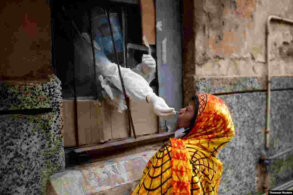 신종 코로나바이러스 감염증 검사를 위해 인도 델리에서 의료진이 보건소 창문을 통해 면봉으로 검체를 채취하고 있다. 