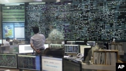 کارمند یک شرکت دولتی در حال نظارت به مانیوتر بزرگی است که عرضه برق را نشان می دهد 