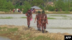 Rohingya people (back) from Rakhine State in Myanmar gather near the border in Ukhiya town, where Bangladeshi border guards were stopping them from entering, Aug. 25, 2017.