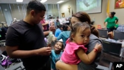 Honduras immigrants seeking asylum, Carlos Fuentes Maldonado, left, stands with his wife, Jennifer Maradiaga, and daughters Mia, 1, and Britany, 4, after they were reunited, July 23, 2018, in San Antonio, Texas.