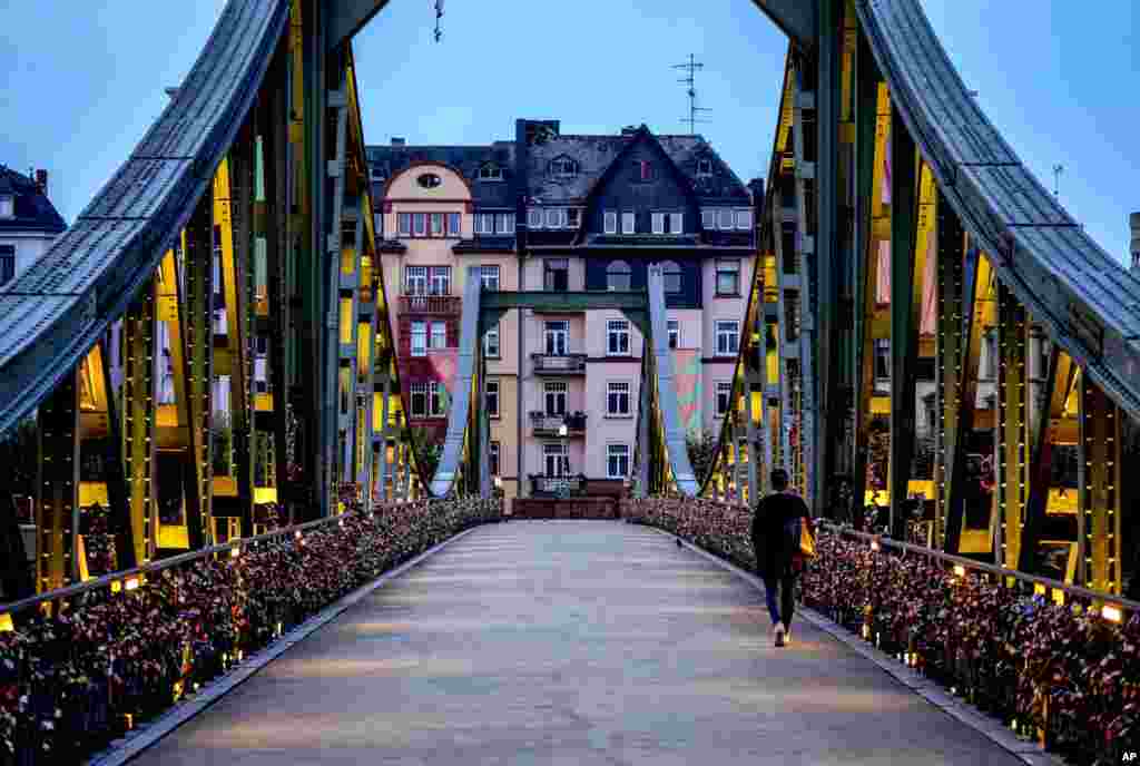 A woman walks over the &quot;Eiserner Steg&quot; (iron footbridge) decorated with love locks in downtown Frankfurt, Germany, Sept. 7, 2021.
