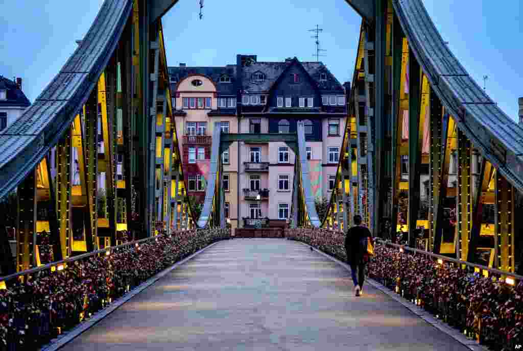 A woman walks over the "Eiserner Steg" (iron footbridge) covered with love locks in downtown Frankfurt, Germany, Sept. 7, 2021.