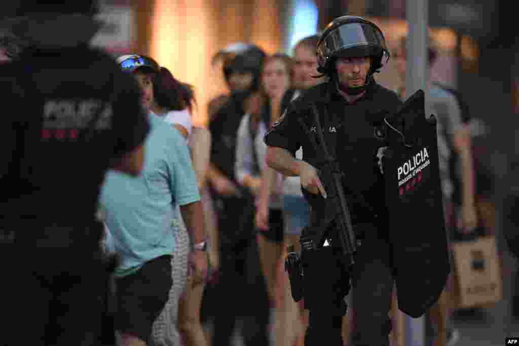 Spanish policemen stand guard in a cordoned off area after a van rammed into a crowd on the Las Ramblas avenue in Barcelona, Aug. 17, 2017.