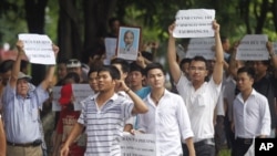 Anti-China protesters hold a portrait of late revolutionary leader Ho Chi Minh and the names of Vietnamese soldiers who were killed by China in 1974 in the Paracel Islands and in 1988 in the Spratly Islands during a demonstration in Hanoi, July 24, 2011.