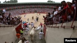 Revelers fall as they enter the bullring following the first running of the bulls at the San Fermin festival in Pamplona, Spain, July 7, 2019.