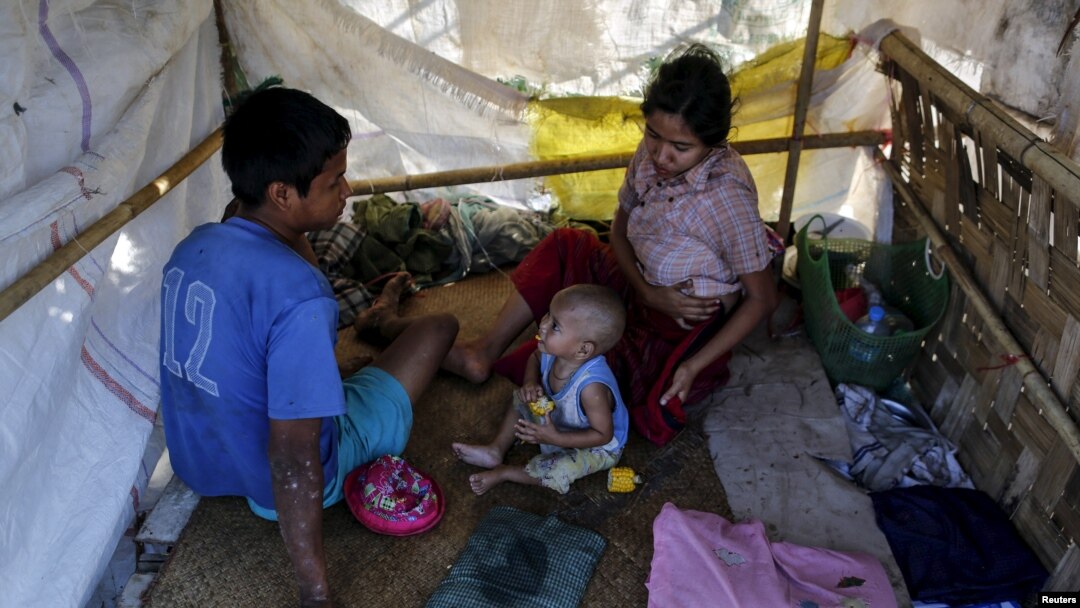 Members of a homeless family pass the time in their temporary shelter beside a street in Yangon, Myanmar, Feb. 4, 2016.