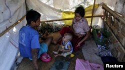 Members of a homeless family pass the time in their temporary shelter beside a street in Yangon, Myanmar, Feb. 4, 2016.