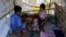 Members of a homeless family pass the time in their temporary shelter beside a street in Yangon, Myanmar, Feb. 4, 2016.