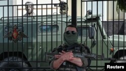 A fighter of Wagner private mercenary group stands guard in a street near the headquarters of the Southern Military District in the city of Rostov-on-Don, Russia, June 24, 2023.