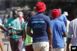 In this April 7, 2020 photo, a man wears a T- shirt with an advertisement regarding contraceptives, in Harare. Lockdowns imposed to curb the coronavirus’ spread have put millions of women in Africa, Asia and elsewhere out of reach of birth control.
