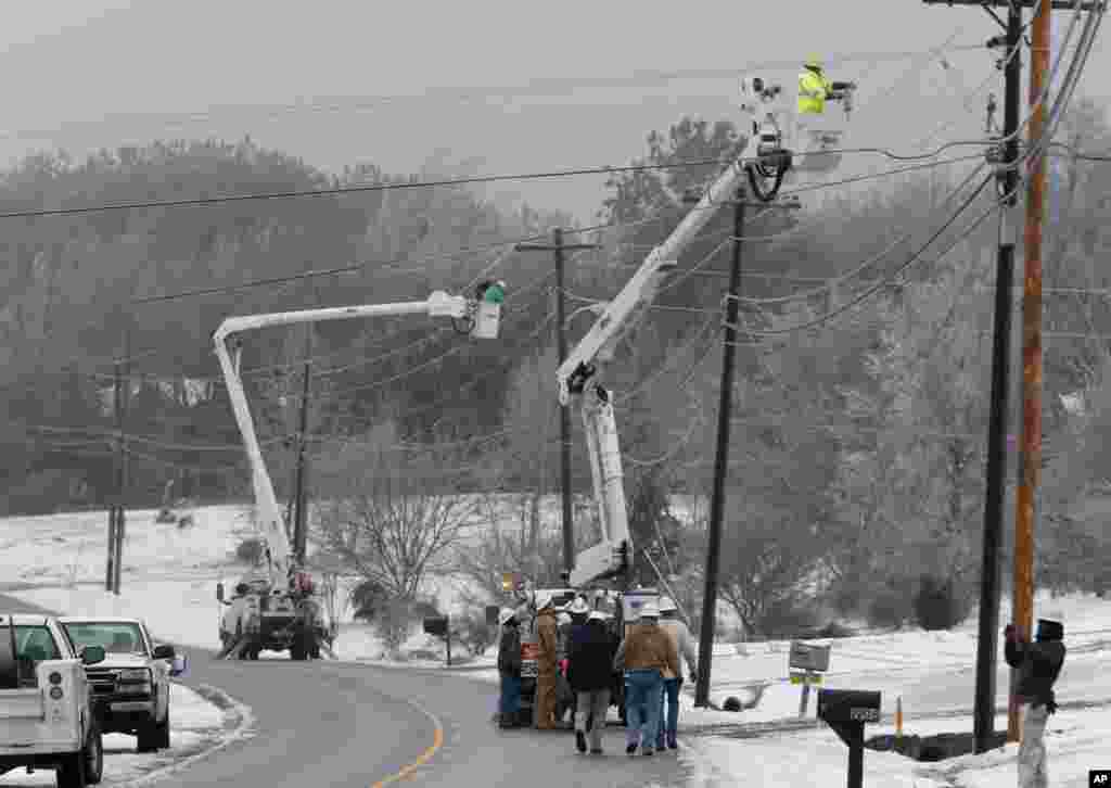 Fort Payne Improvement Authority workers work on lines that had become heavy with ice and were being blown around by high winds in Dog Town, Alabama, Feb. 12, 2014.