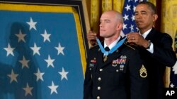 Presiden AS Barack Obama mengalungkan gelar kehormatan tertinggi militer AS kepada Sersan Angkatan Darat Ty Carter di Gedung Putih (26/8).
