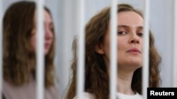 FILE - Belarusian journalists Katsiaryna Andreyeva and Darya Chultsova stand inside a defendants' cage during a court hearing in Minsk, Belarus, Feb. 18, 2021.