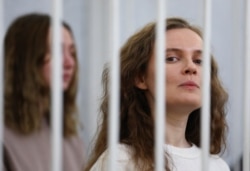 FILE - Katsiaryna Andreyeva and Darya Chultsova, Belarusian journalists, stand inside a defendants' cage during a court hearing in Minsk, Belarus, Feb. 18, 2021.