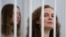Katsiaryna Andreyeva and Darya Chultsova, Belarusian journalists, stand inside a defendants' cage during a court hearing in Minsk, Feb. 18, 2021.