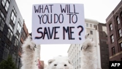 FILE - A anti-global warming protester holds up a sign in Cleveland, Ohio, near the Republican National Convention, July 18, 2016.