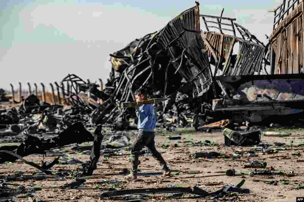 A boy carries an unexploded Rocket Propelled Grenade at the site of the previous evening's Israeli airstrike that targeted shipments of weapons that belonged to Syrian government forces in Qamishli, in mainly Kurdish northeastern Syria, Dec. 10, 2024.