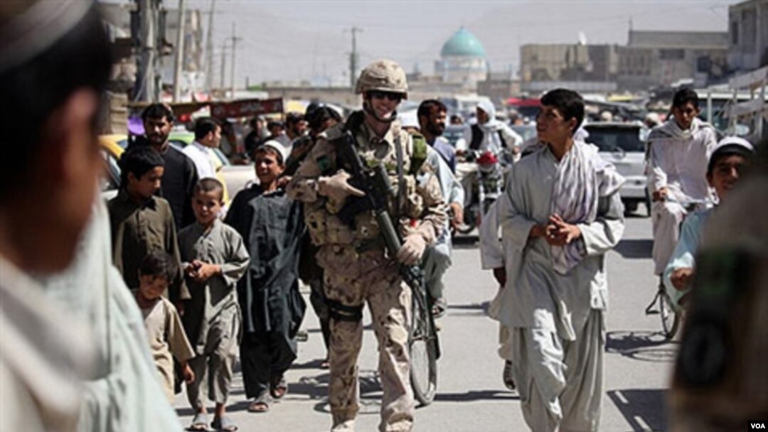 Tentara NATO berbincang dengan warga setempat di kota Kandahar.
