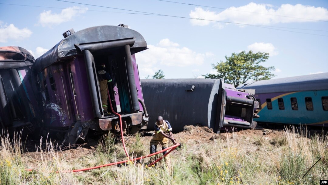 Seorang petugas pemadam kebakaran menarik selang di samping kereta yang anjlok setelah kecelakaan dekat Kroonstad di Provinsi Free State, Afrika Selatan, 110 kilometer barat daya Johannesburg, 4 Januari 2018.