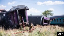 Seorang petugas pemadam kebakaran menarik selang di samping kereta yang anjlok setelah kecelakaan dekat Kroonstad di Provinsi Free State, Afrika Selatan, 110 kilometer barat daya Johannesburg, 4 Januari 2018.