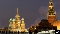 FILE - People walk in Red Square, with St. Basil Cathedral, left, the Kremlin's Spassky Tower, right rear, and the Lenin Mausoleum, right, in Moscow.
