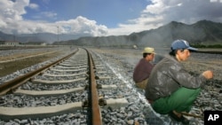FILE - Workers take a break sitting on the tracks leading to the platform of the newly opened Lhasa train station in Lhasa, Tibet, China.