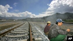 FILE - Workers take a break sitting on the tracks leading to the platform of the train station in Lhasa, Tibet, China. First announced last week, the 1,800-kilometer (1,120-mile) line would link Lhasa with the western metropolis of Chengdu with an estimated travel time of 13 hours.