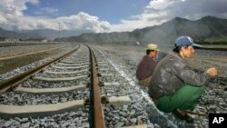 FILE - Workers take a break sitting on the tracks leading to the platform of the train station in Lhasa, Tibet, China. First announced last week, the 1,800-kilometer (1,120-mile) line would link Lhasa with the western metropolis of Chengdu with an estimated travel time of 13 hours.