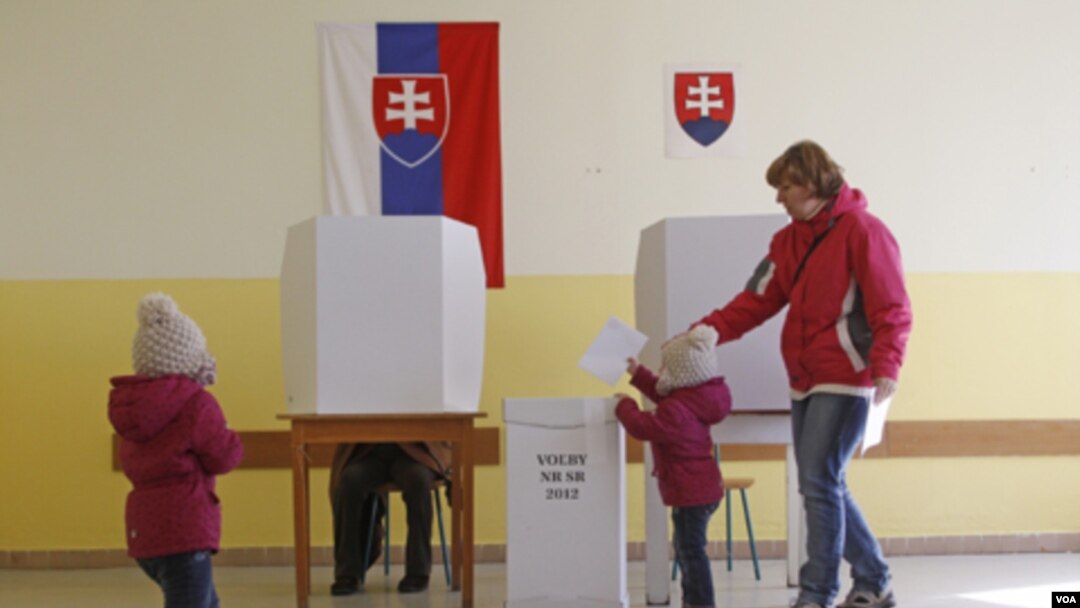 Seorang anak memasukkan surat suara ke dalam kotak suara di Bratislava, Slovakia (10/3).
