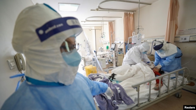 Trabajadores médicos fuertemente protegidos atienden a pacientes de coronavirus en la ciudad china de Wuhan, el 17 de febrero de 2020.