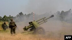 Des soldats des Forces armées de la République démocratique du Congo (FARDC) tirent une pièce d'artillerie mobile lors de l'opération Sokola 1 à Matombo, à 35 km au nord de Beni, au Nord-Kivu, le 13 janvier 2018..