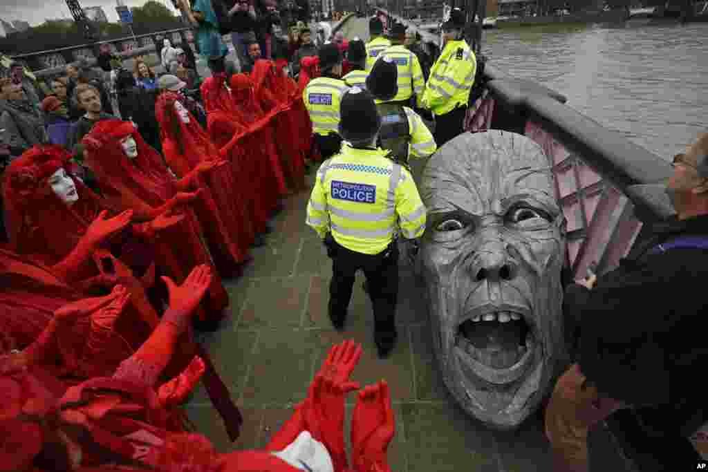 Environmental protesters gather around the head of a statue confiscated by police on Lambeth bridge in central London.