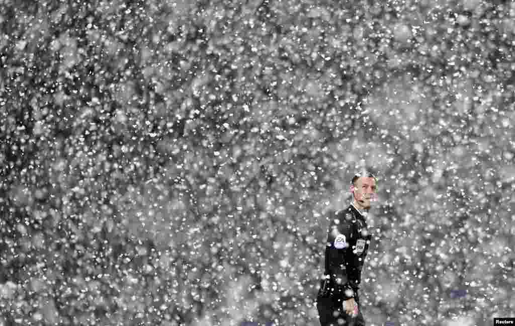 Referee Mark Clattenburg stands in the snow during the English Premier League soccer match between Manchester City and West Bromwich Albion at The Hawthorns in West Bromwich, central England.