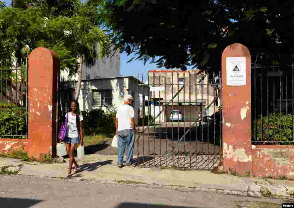 Una mujer lleva contenedores de agua que consiguió de un grupo de la iglesia que ofrece a los residentes pequeñas cantidades para frenar la escasez. En La Habana, Cuba, el 12 de septiembre de 2024.