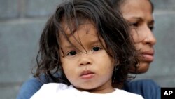 Jesús Funes, de 19 meses, es sostenido por su madre, Diva Funes, ambos inmigrantes de Honduras, tras ser esoltados de regreso a Reynosa, México, el jueves, 21 de junio de 2018. La familia, que buscaba asilo, fue advertida por funcionarios que si cruzaba ilegalmente sería separados por lo que decidieron retornar voluntariamente.