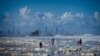 Tourists walk on the Currumbin Beach covered with foam in the wake of cyclonic conditions after wild weather lashed Australia&#39;s Northern New South Wales and South East Queensland with heavy rain, strong winds and king tides.