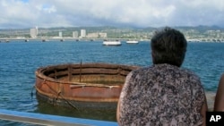 This Nov. 21, 2014 photo shows visitors looking out at the sunken USS Arizona from a memorial atop the rusting battleship in Pearl Harbor, Hawaii. 