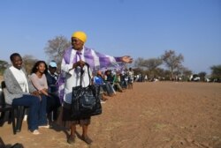 A woman talks to other voters while waiting in a queue to vote at a polling station in Gaborone, Botswana, Oct. 23, 2019.