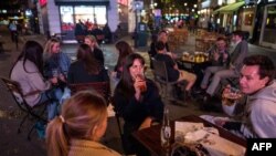 People drink at the outside tables of a bar in central London on Sept. 24, 2020, on the first day of the new earlier closing times for pubs and bars in England and Wales, introduced to combat the spread of the coronavirus. 