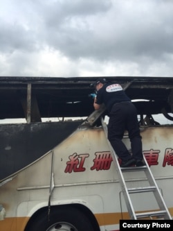 台湾桃园警方查看烧毁的旅游大巴，事故造成24名大陆游客、1名司机和1名导游遇难（台湾行政院提供 ）