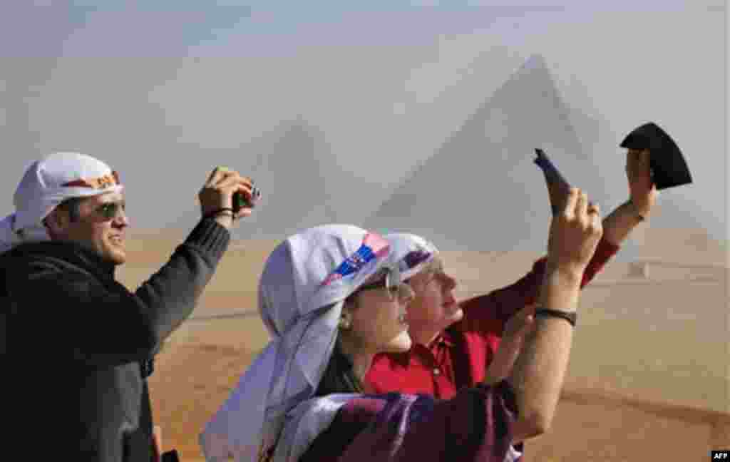 Venezuelan tourists watch a partial solar eclipse in front of the Giza Pyramids, Egypt, Tuesday, Jan. 4, 2011. A partial solar eclipse began Tuesday in the skies over the Mideast and will extend across much of Europe. (AP Photo/Amr Nabil)