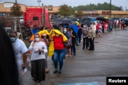 Orang-orang berbaris untuk memberikan suara mereka untuk pemilihan presiden yang akan datang karena pemungutan suara ketika badai tropis Zeta mendekati Pantai Teluk di New Orleans, Louisiana, AS, 27 Oktober 2020. (Foto: REUTERS/Kathleen Flynn)