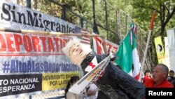 An activist hits a pinata resembling U.S. President Donald Trump as they mark the one-year anniversary of Trump's inauguration with a protest outside the U.S. embassy in Mexico City, Mexico, Jan. 20, 2018.