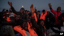 Migrants and refugees from different African nationalities sailing adrift on an overcrowded rubber boat, receive life jackets from aid workers of the Spanish NGO Open Arms in the Mediterranean Sea, international waters, off the Libyan coast, Friday,…