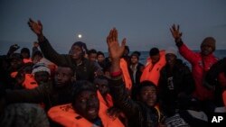 Migrants and refugees of different African nationalities, sailing adrift on an overcrowded rubber boat, receive life jackets from aid workers of the Spanish NGO Open Arms in the Mediterranean Sea, off the Libyan coast, Jan. 10, 2020.